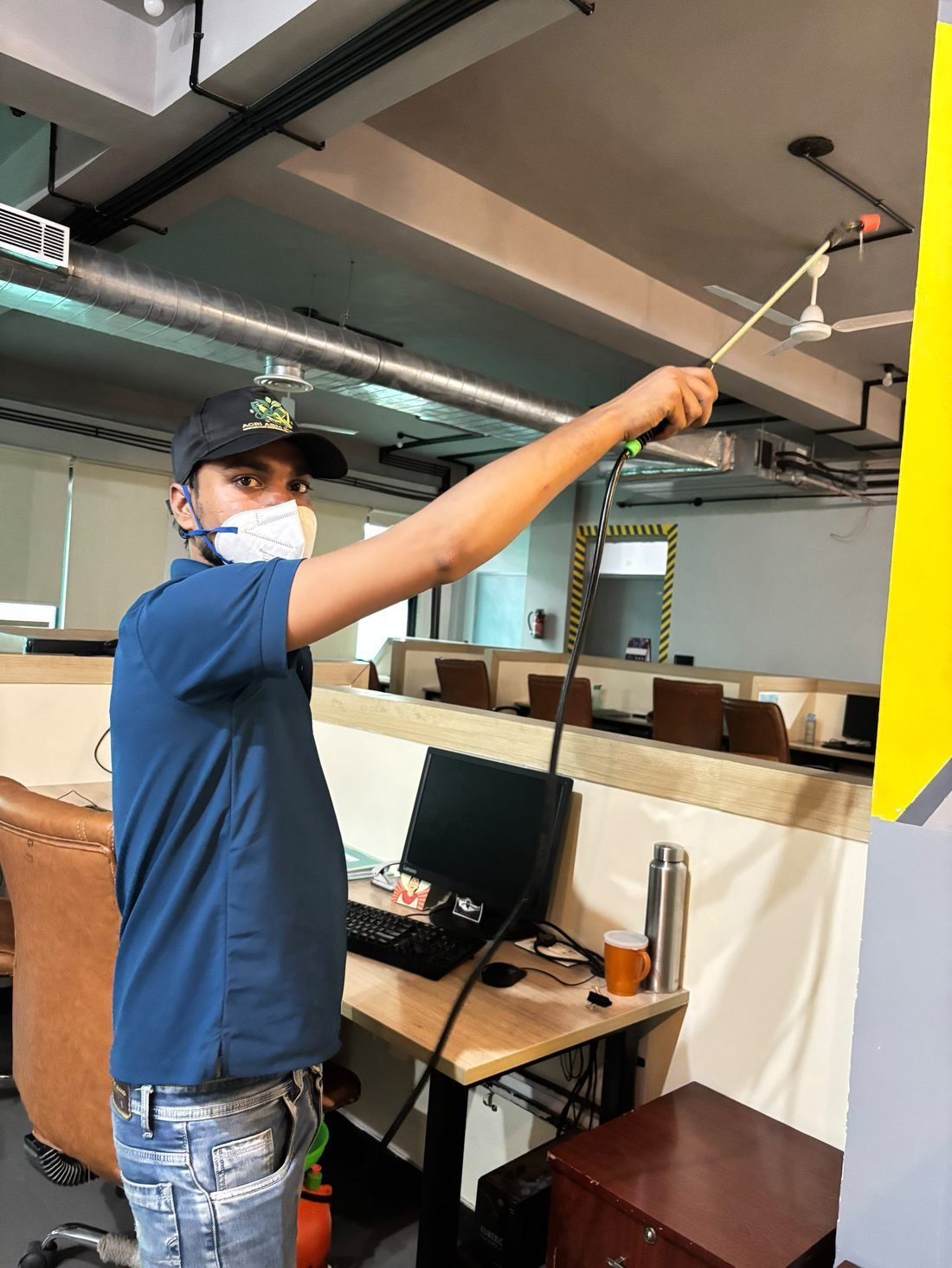 Agri ABM Pvt Ltd technician treating office ceiling area near workstations