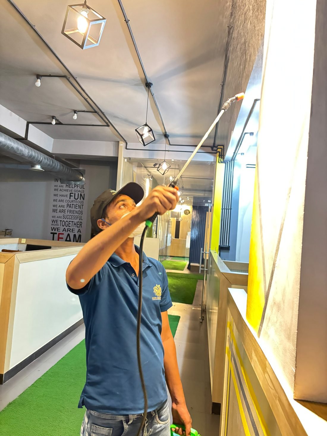 Agri ABM Pvt Ltd technician spraying ceiling treatment in a commercial office corridor